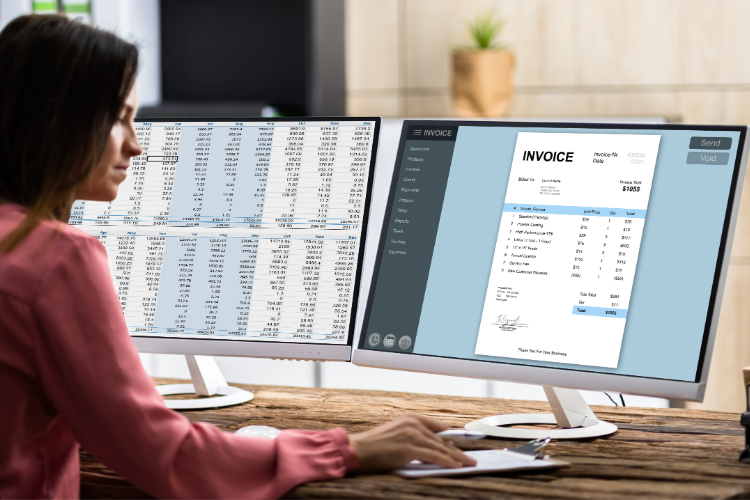 A woman is at a desk with two monitors, engaging in Xero Training by entering sales invoices.