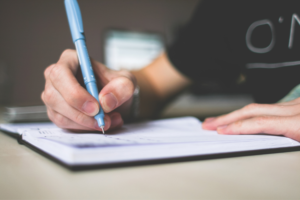 A person using a pen to write in a notebook while undergoing Xero Training.