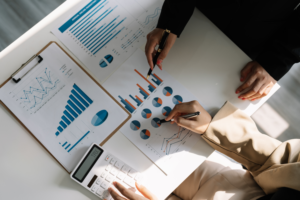 Two business people utilizing Xero for tax planning and advisory while examining graphs on a table.