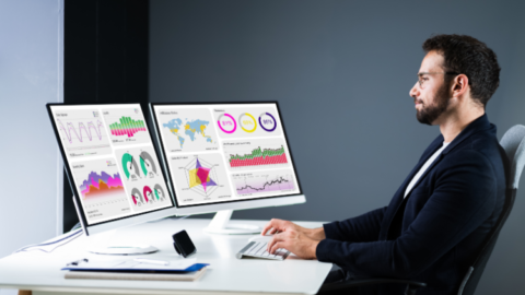 Businessperson sitting at a desk working at a computer - JacRox