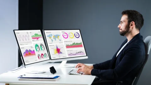 Businessperson sitting at a desk working at a computer - JacRox