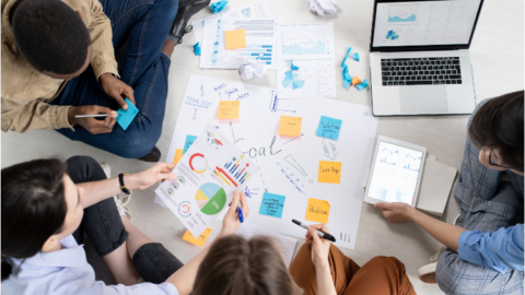 A group of people working on a project at a table. - JacRox